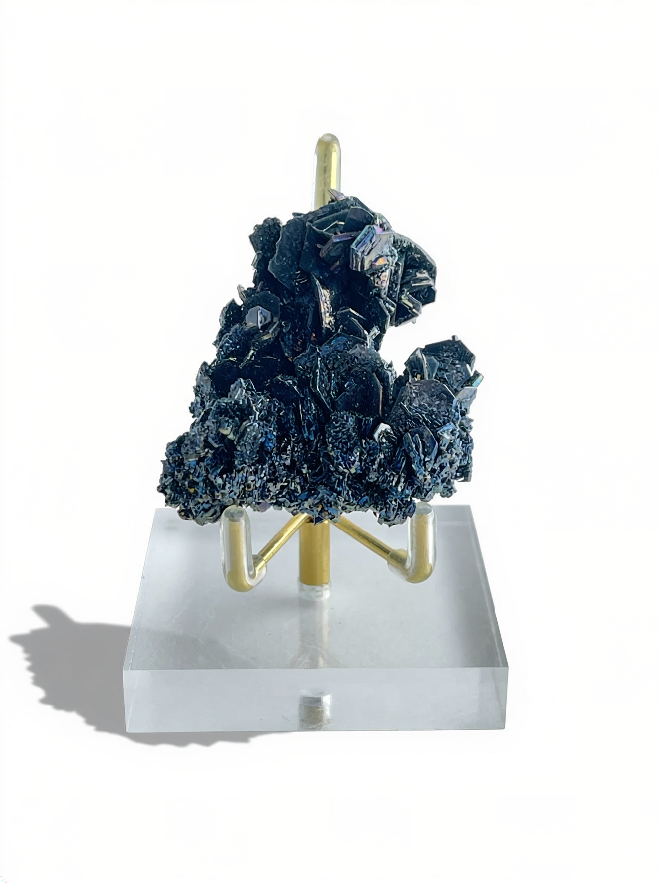 Rainbow Carborundum cluster mineral specimen displayed on a stand, showing dark metallic crystals with iridescent blue and violet reflections.