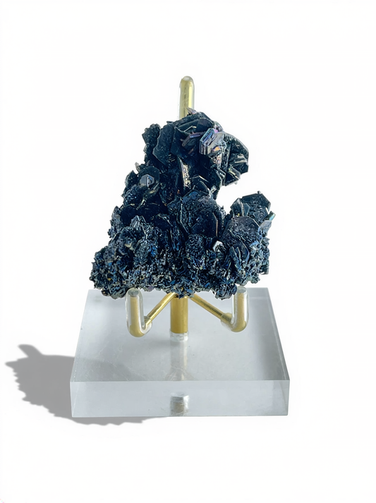 Rainbow Carborundum cluster mineral specimen displayed on a stand, showing dark metallic crystals with iridescent blue and violet reflections.