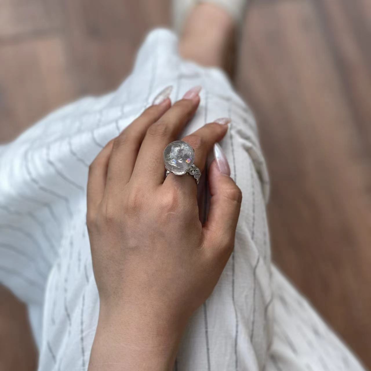 Close up of Rainbow Quartz Sphere ring on hand showing internal rainbow flashes