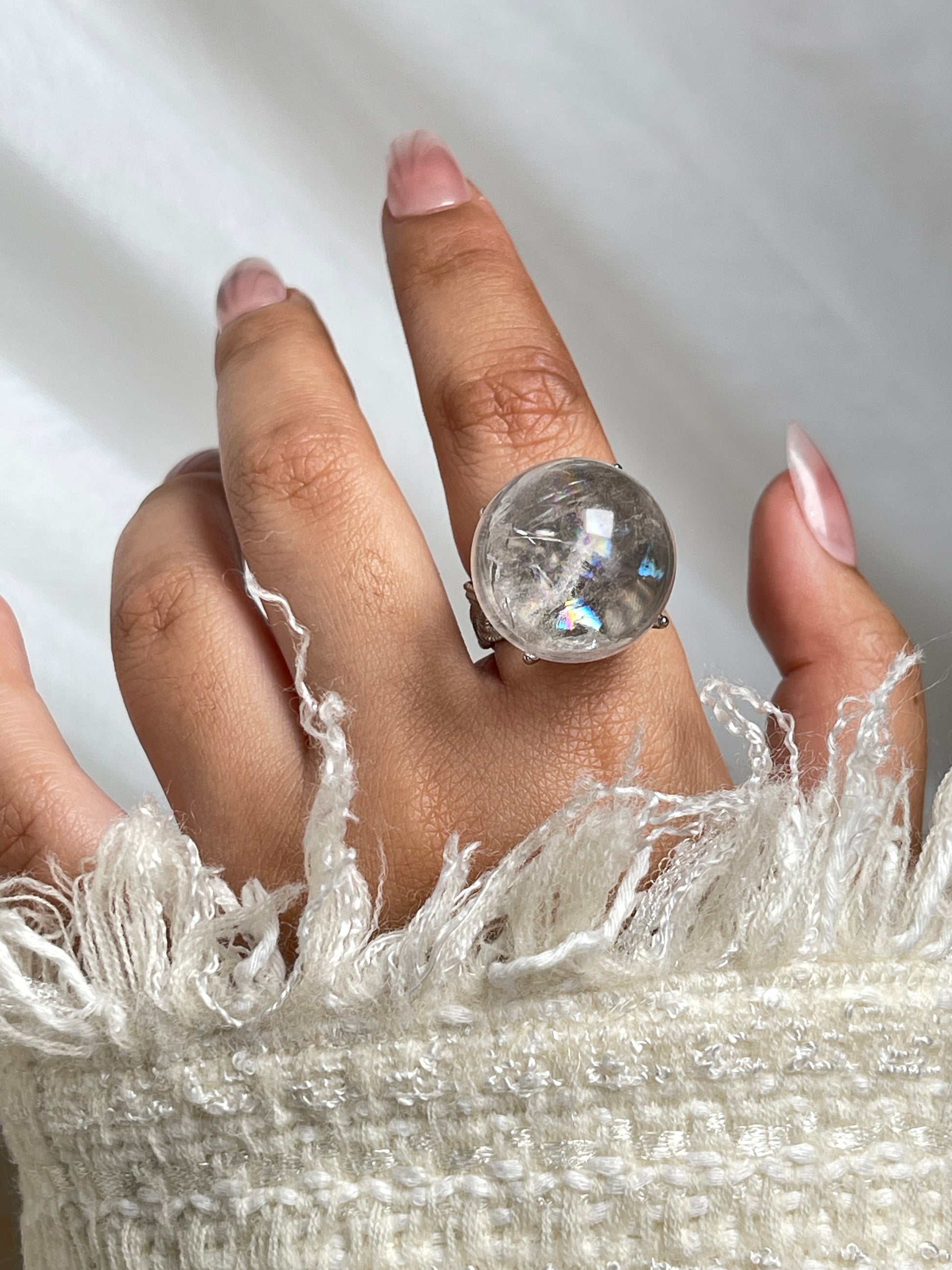 Close up of Rainbow Quartz Sphere ring on hand showing internal rainbow flashes