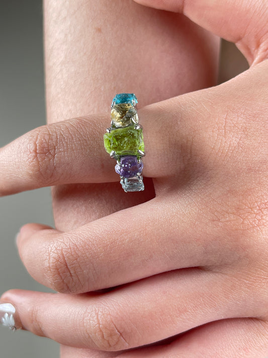Close-up of rainbow raw crystal ring with aquamarine citrine peridot amethyst and blue apatite worn on hand