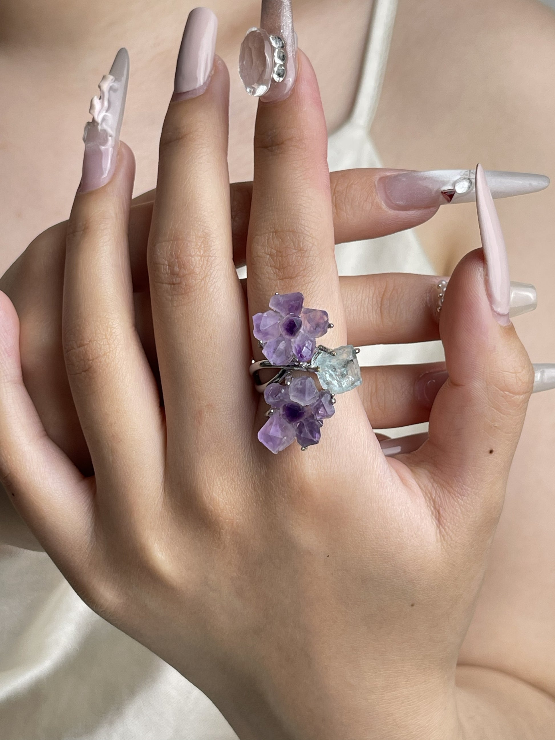 Hand wearing raw Amethyst flower and Aquamarine natural crystal ring