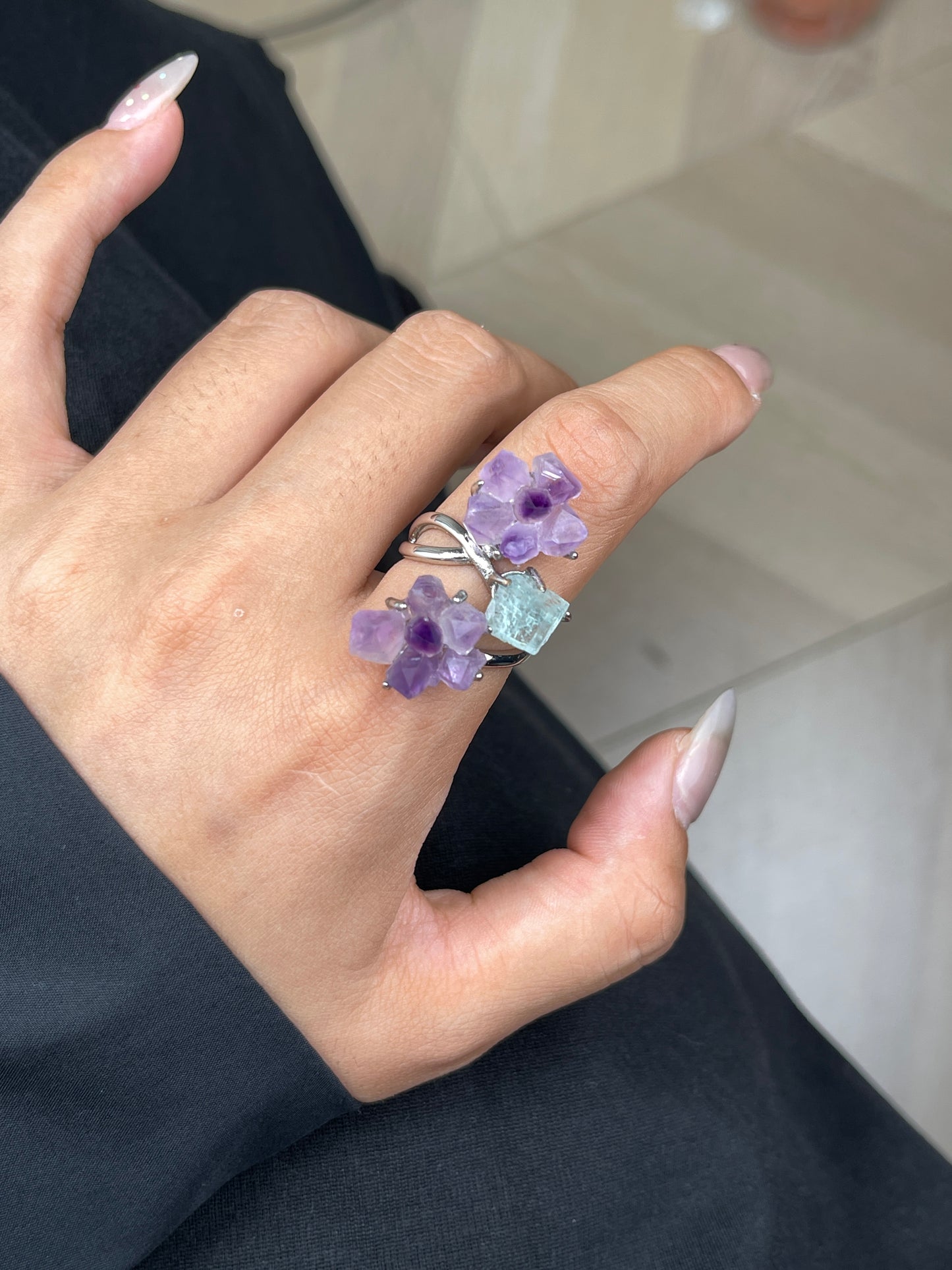 Close up hand wearing raw Amethyst flower and Aquamarine crystal ring