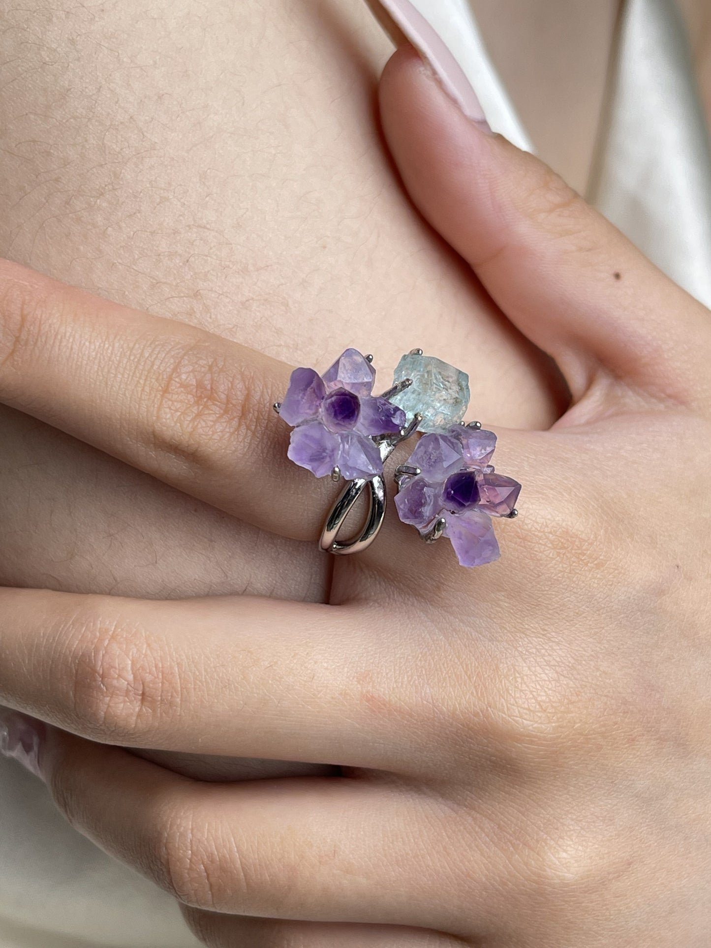 Close up hand wearing raw Amethyst flower and Aquamarine crystal ring