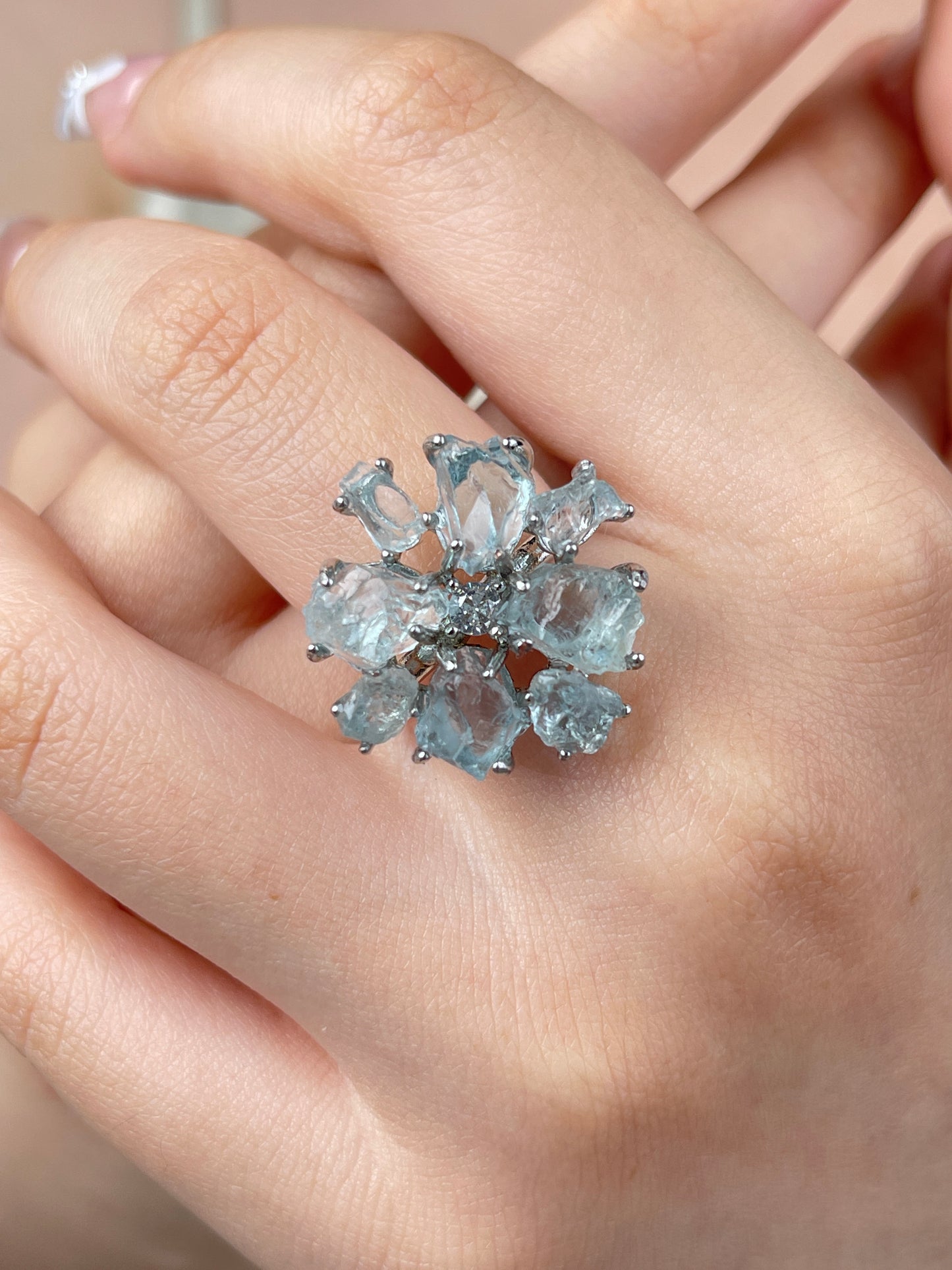 Raw aquamarine crystal ring worn on hand with soft icy blue natural crystal details