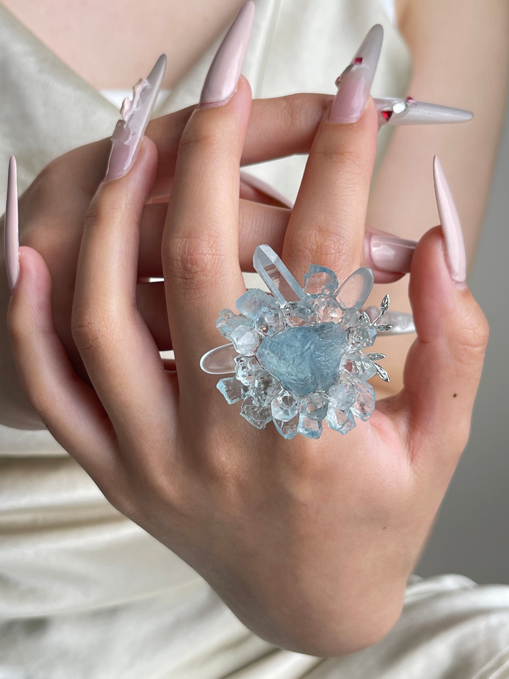 Raw aquamarine and quartz flower ring worn on hand