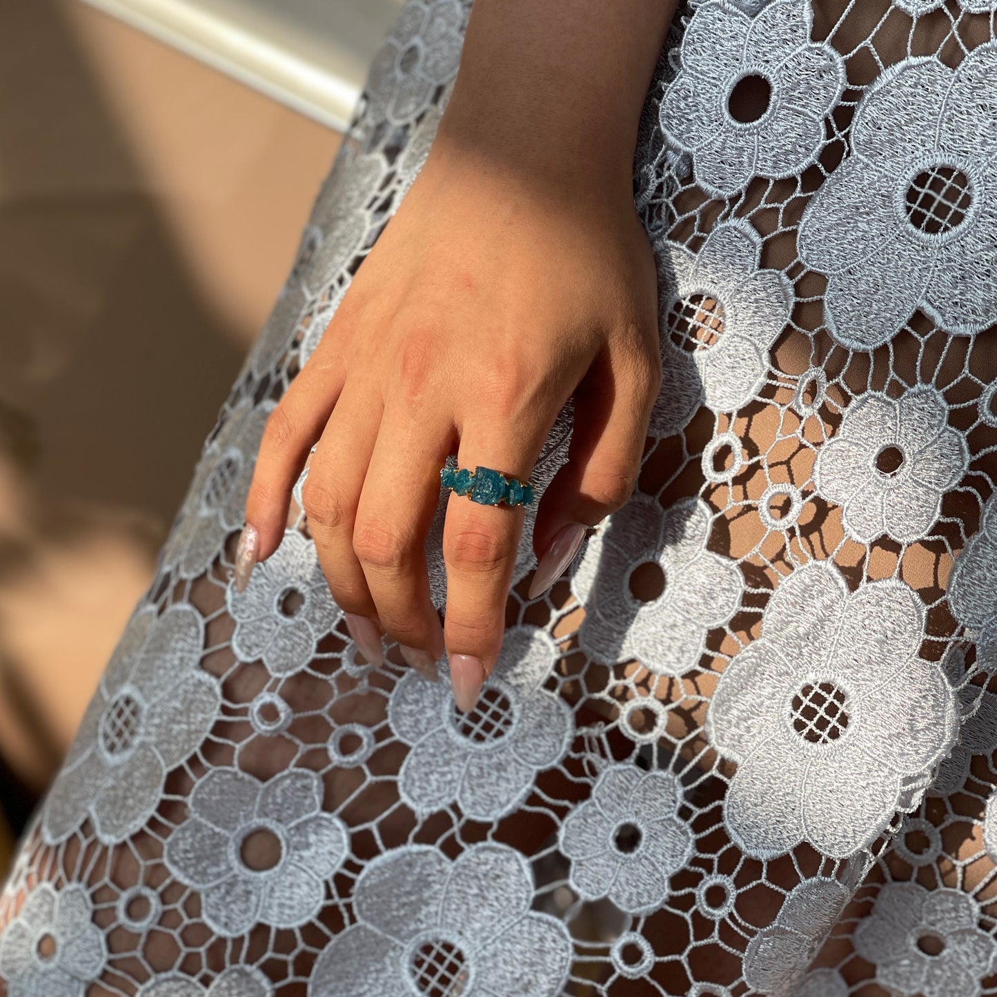 Close-up of Raw Blue Apatite row ring worn on hand