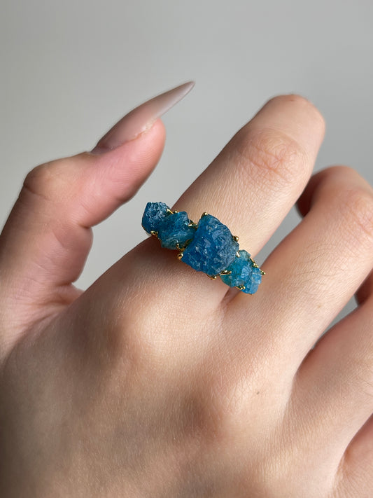 Close-up of Raw Blue Apatite row ring worn on hand