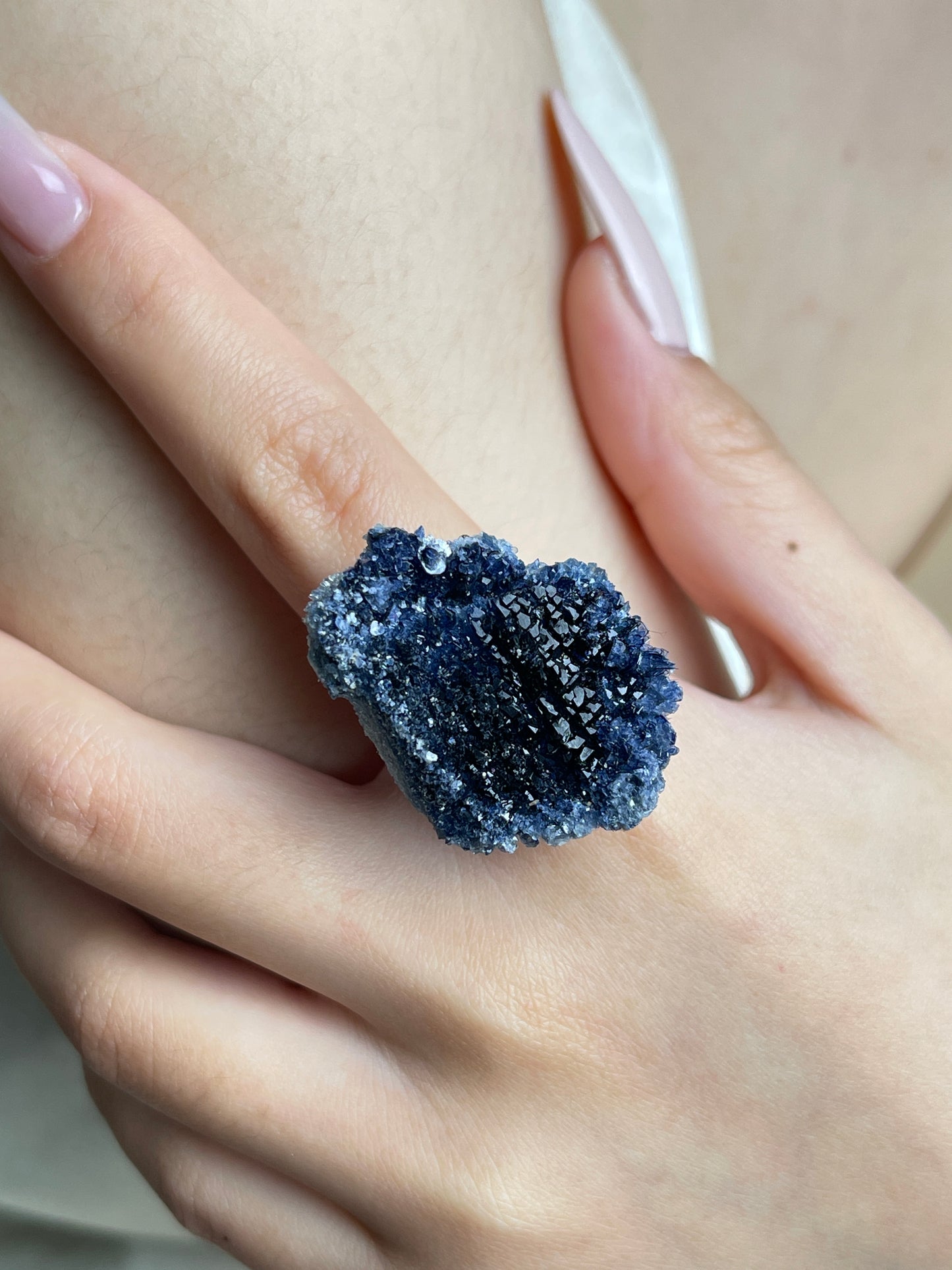 Close-up hand view of a raw Blue Sapphire crystal cluster ring.