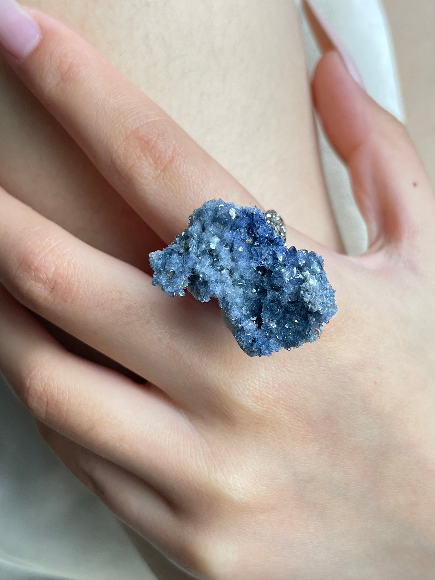 Close-up hand view of a raw Blue Sapphire crystal ring.