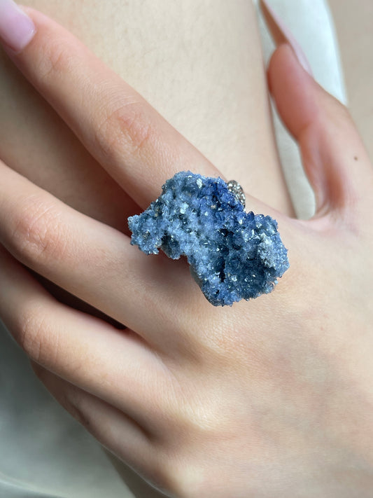 Close-up hand view of a raw Blue Sapphire crystal ring.