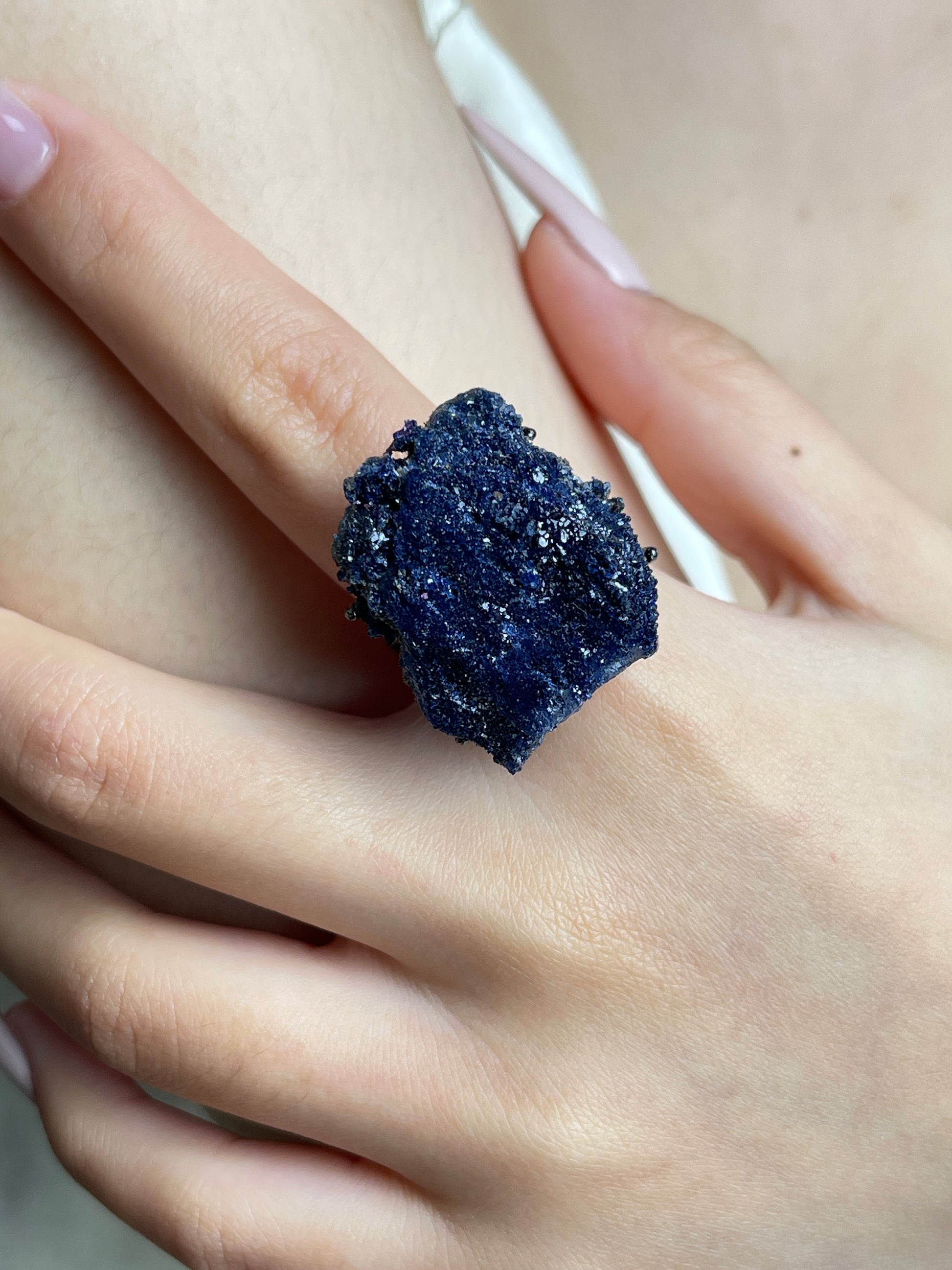 Close-up hand view of a raw Blue Sapphire mineral specimen ring.