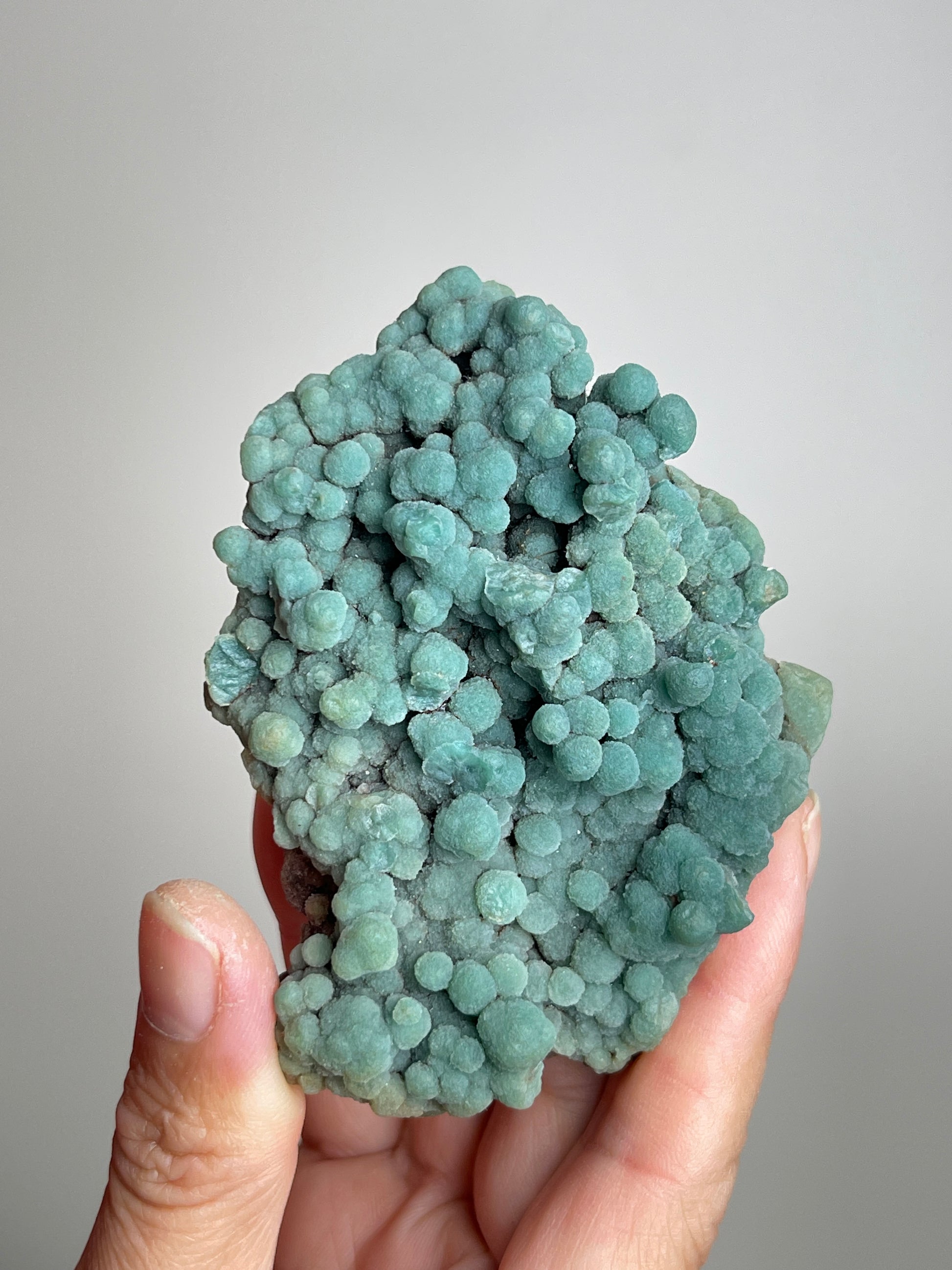 Handheld raw botryoidal green prehnite mineral specimen showing natural size and texture