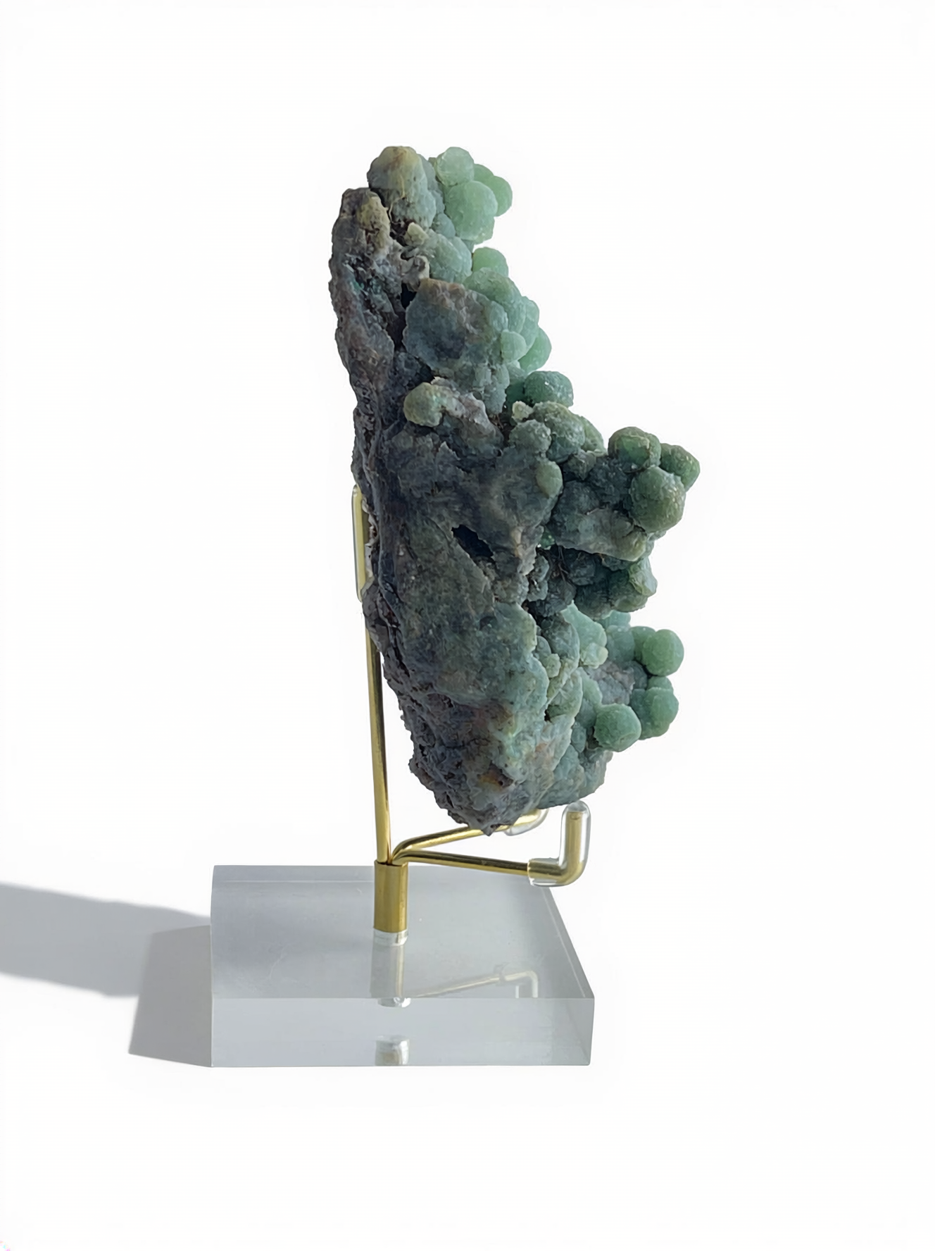 Side view of raw botryoidal green prehnite mineral specimen on display stand