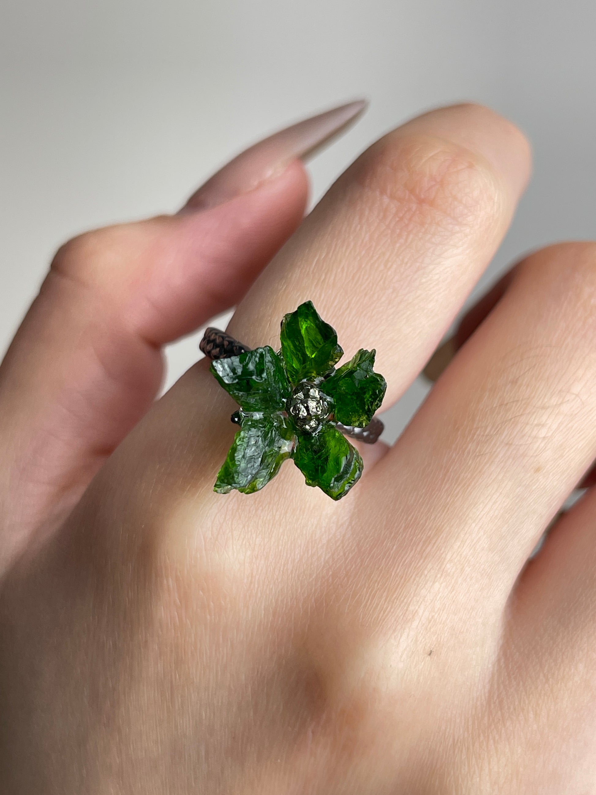 Close-up of Raw Chrome Diopside and Chalcopyrite flower ring worn on hand