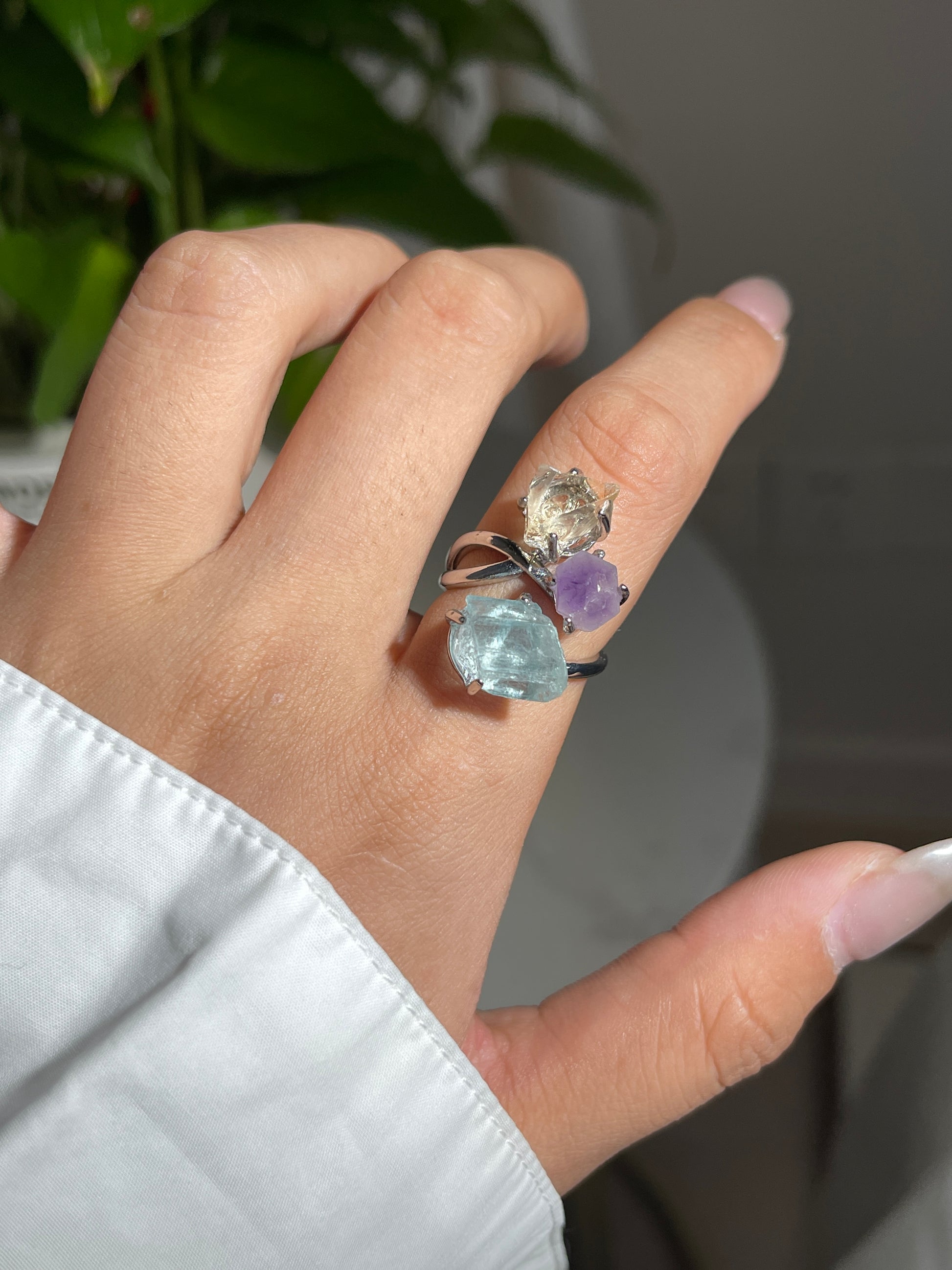 Close up of raw citrine, raw amethyst and raw aquamarine ring worn on hand