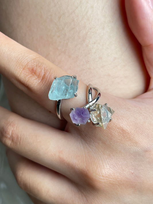 Close up of raw citrine, raw amethyst and raw aquamarine ring worn on hand