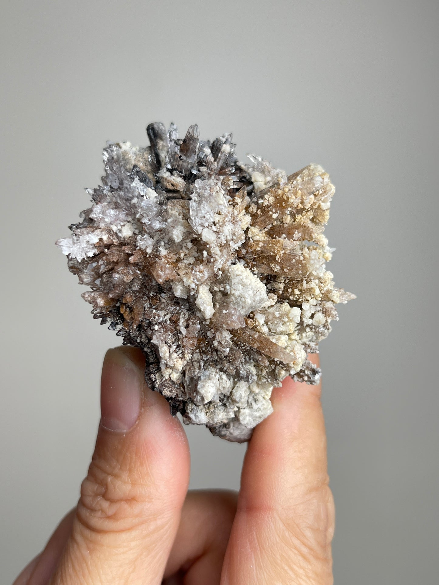 Handheld Raw Creedite cluster mineral specimen showing natural size and texture