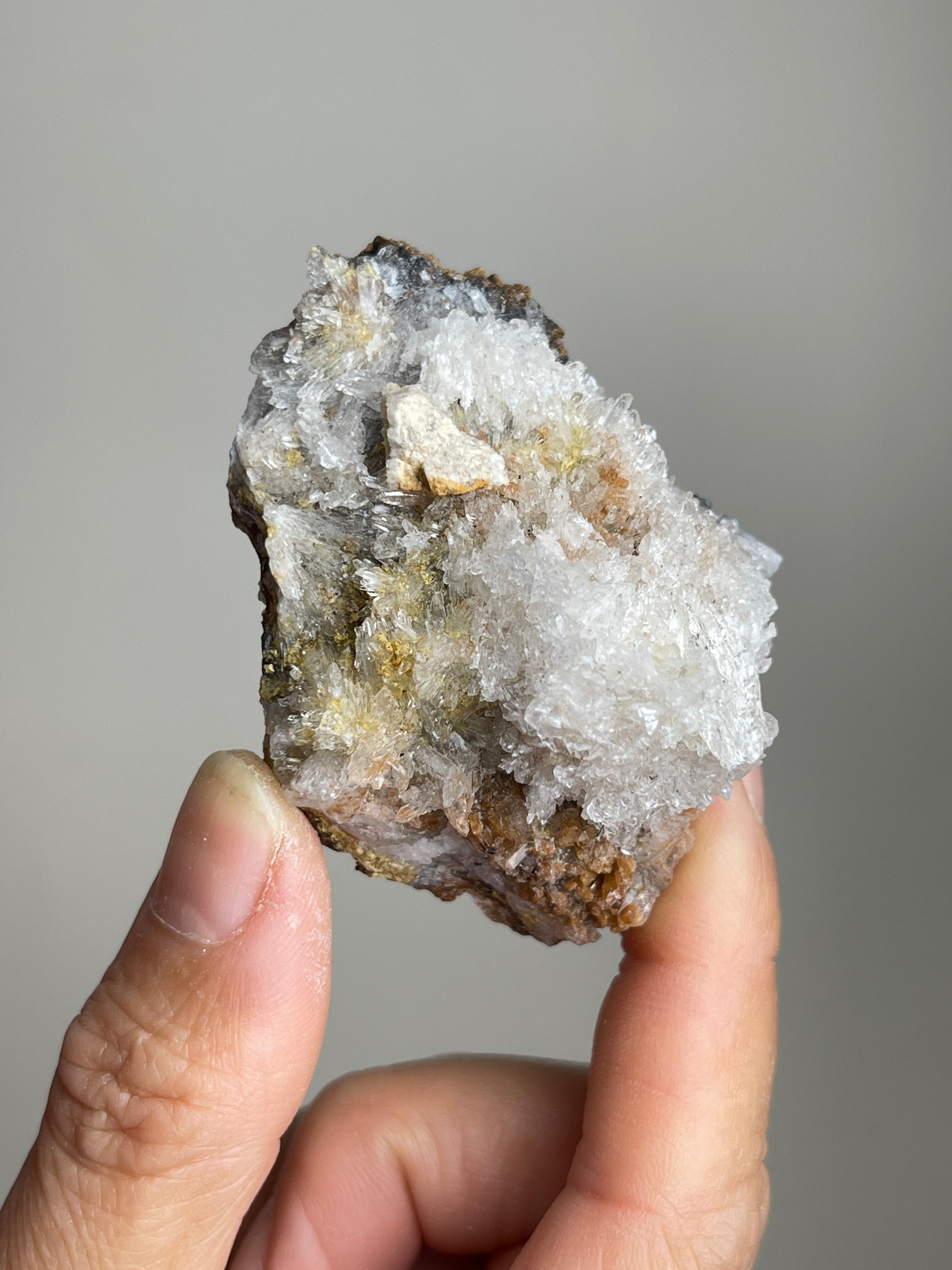 Handheld Raw Creedite cluster mineral specimen showing natural size and texture