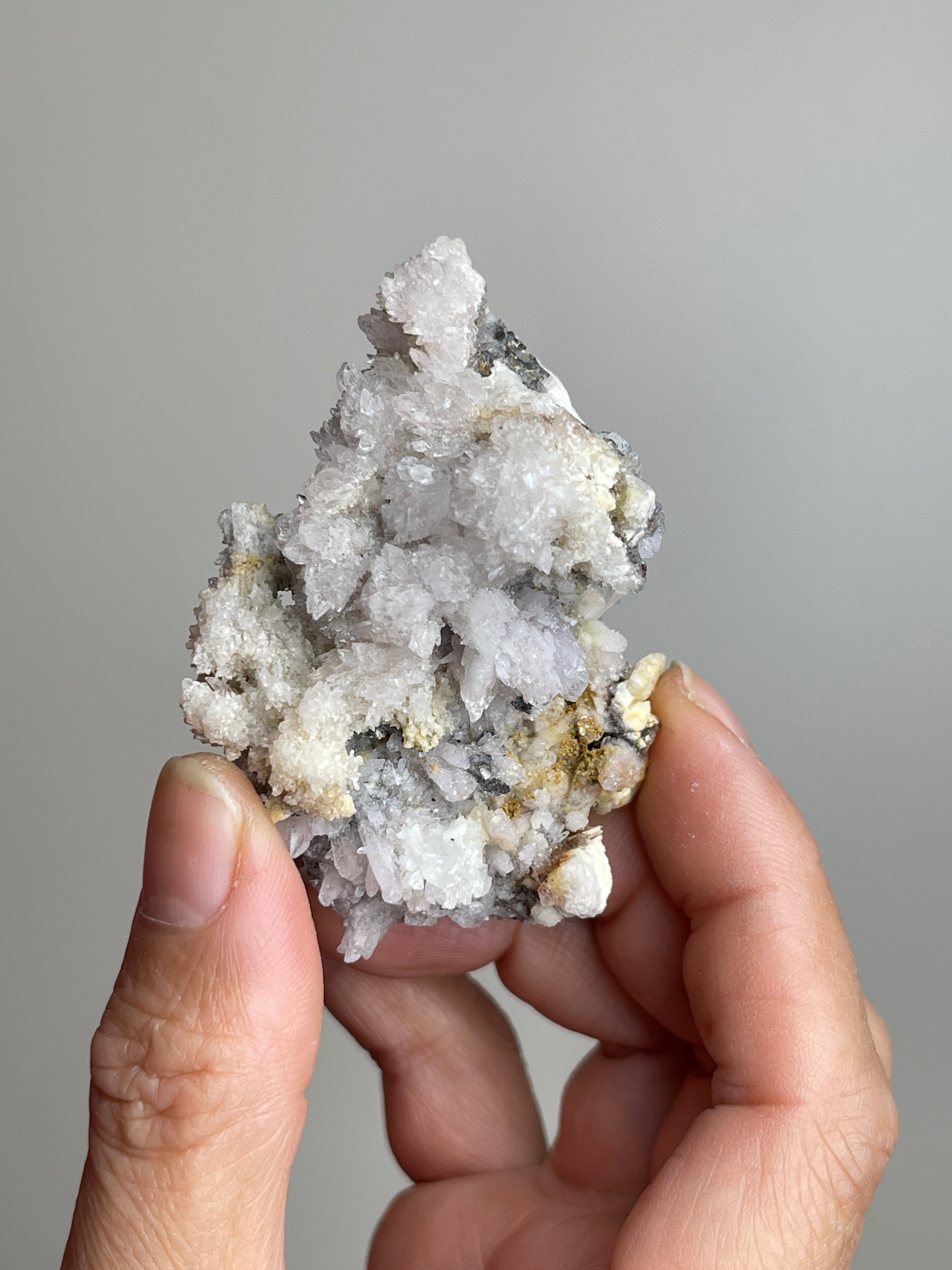 Handheld Raw Creedite cluster mineral specimen showing natural size and texture