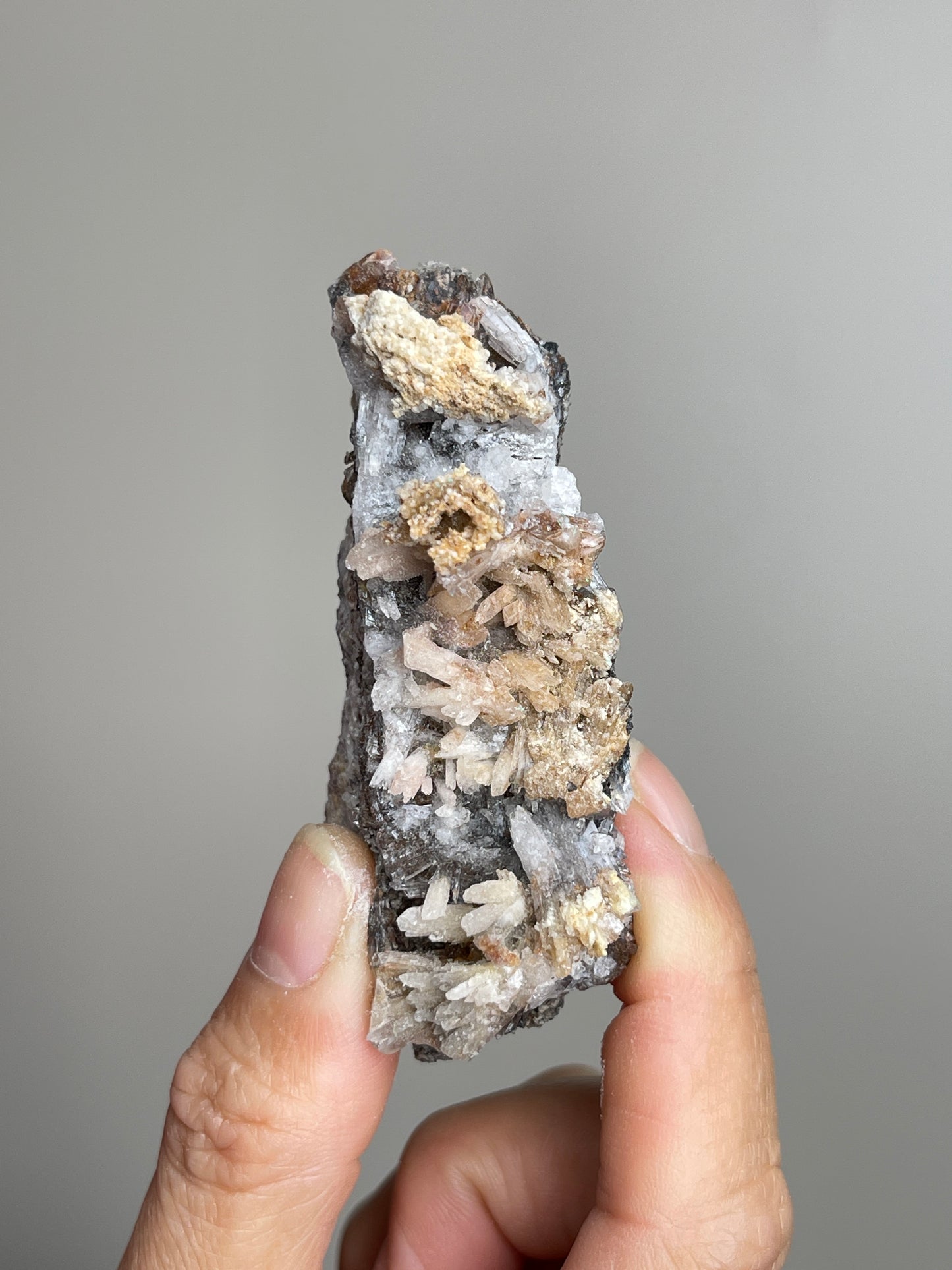 Handheld Raw Creedite flower mineral specimen showing natural size and vertical form