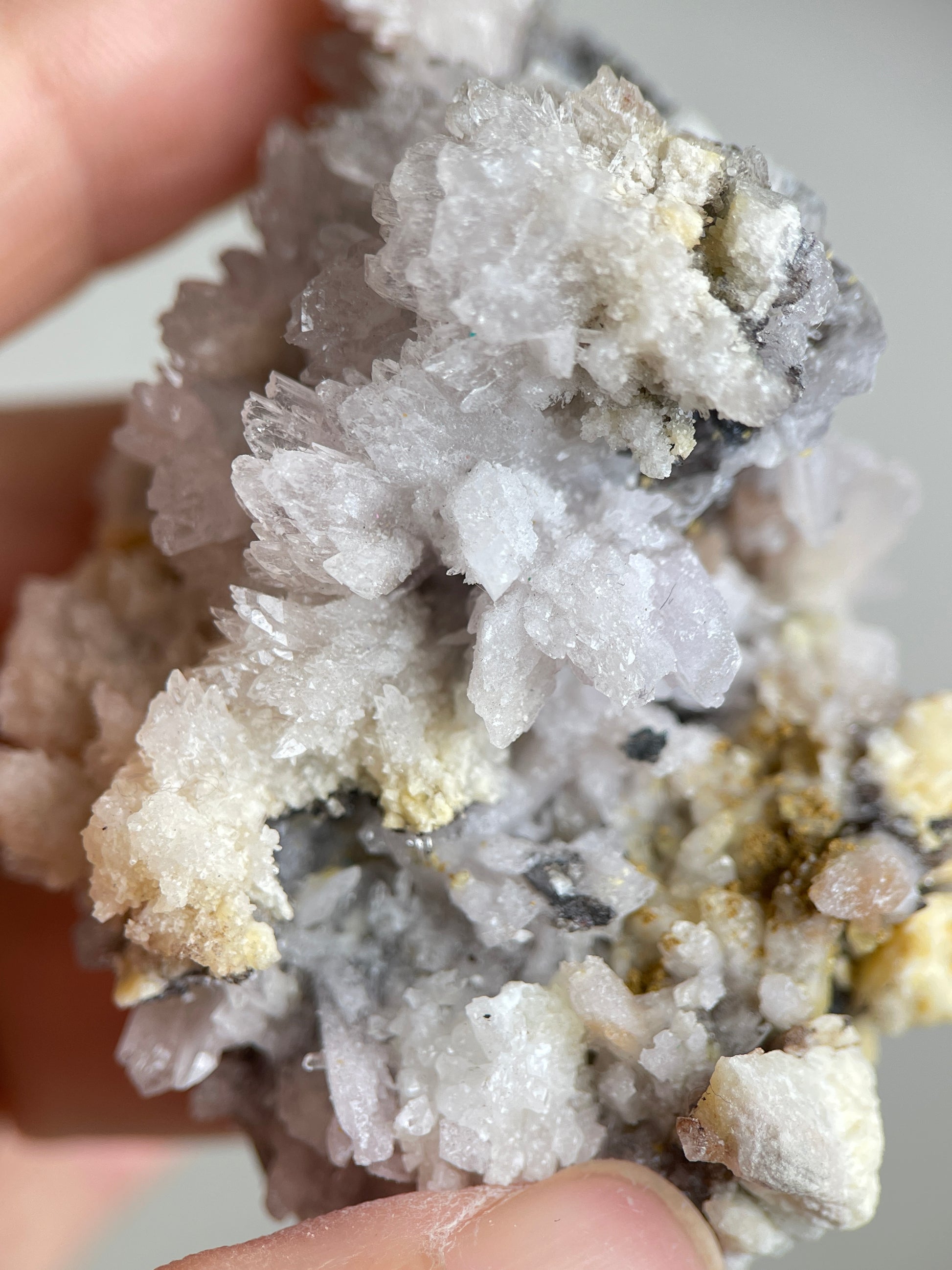 Close-up of pale white Creedite crystal clusters on natural matrix