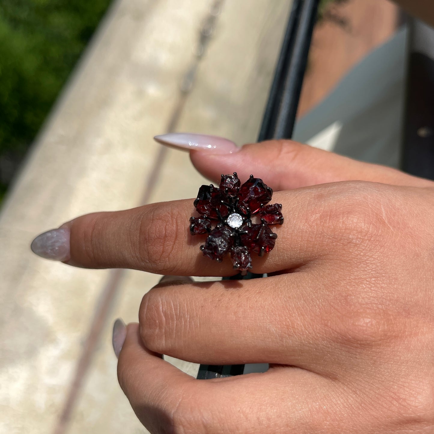 Raw garnet snowflake ring worn on hand, showing deep red garnet crystals and gunmetal-tone band