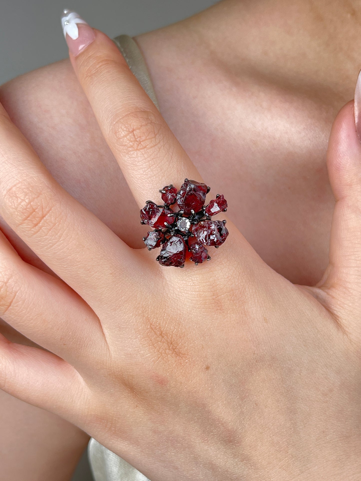 Raw garnet snowflake ring worn on hand, showing deep red garnet crystals and gunmetal-tone band
