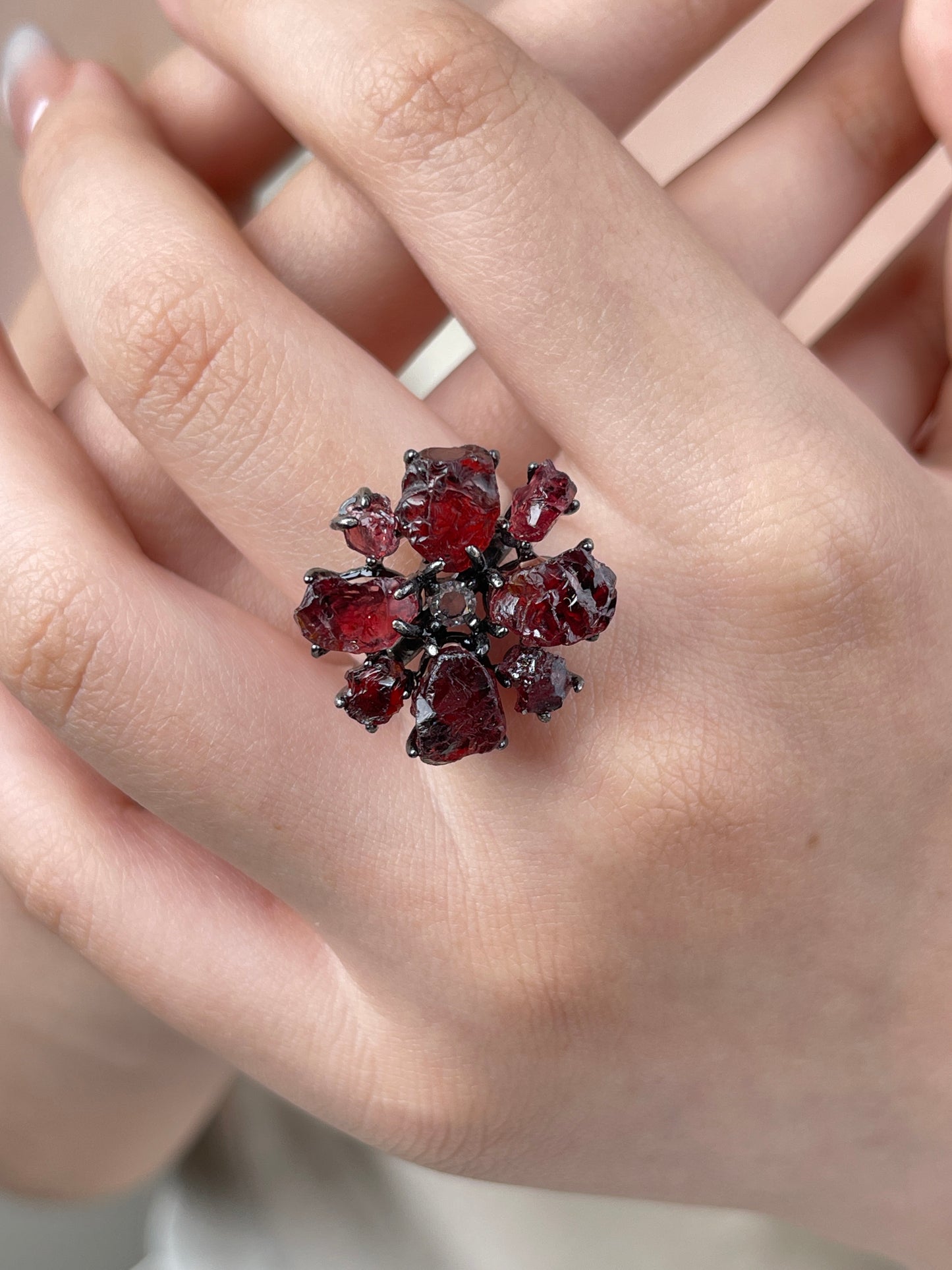 Raw garnet snowflake ring worn on hand, featuring deep red natural garnet crystals in a bold snowflake design