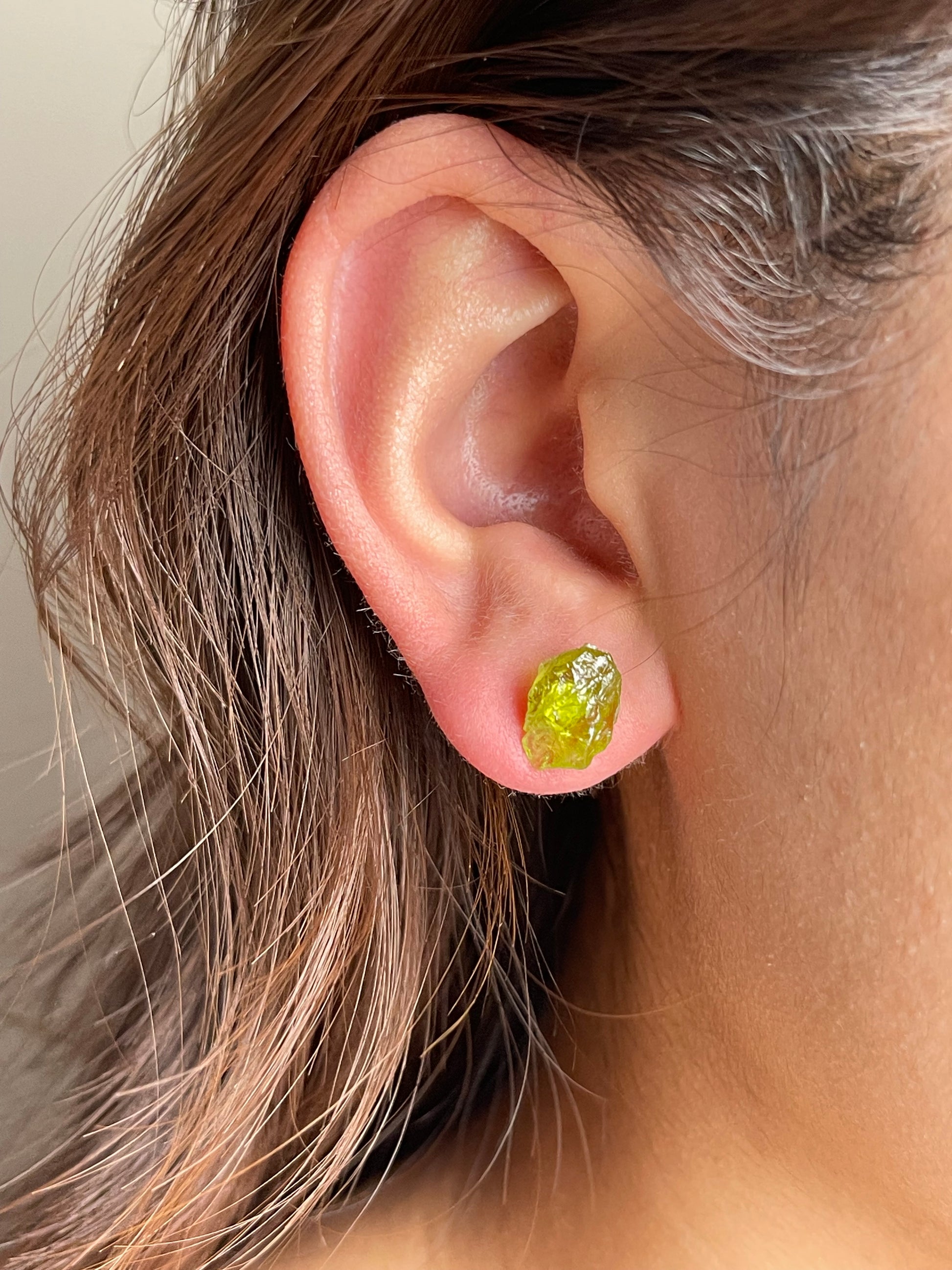 Raw Peridot Stud Earrings close-up worn on ear