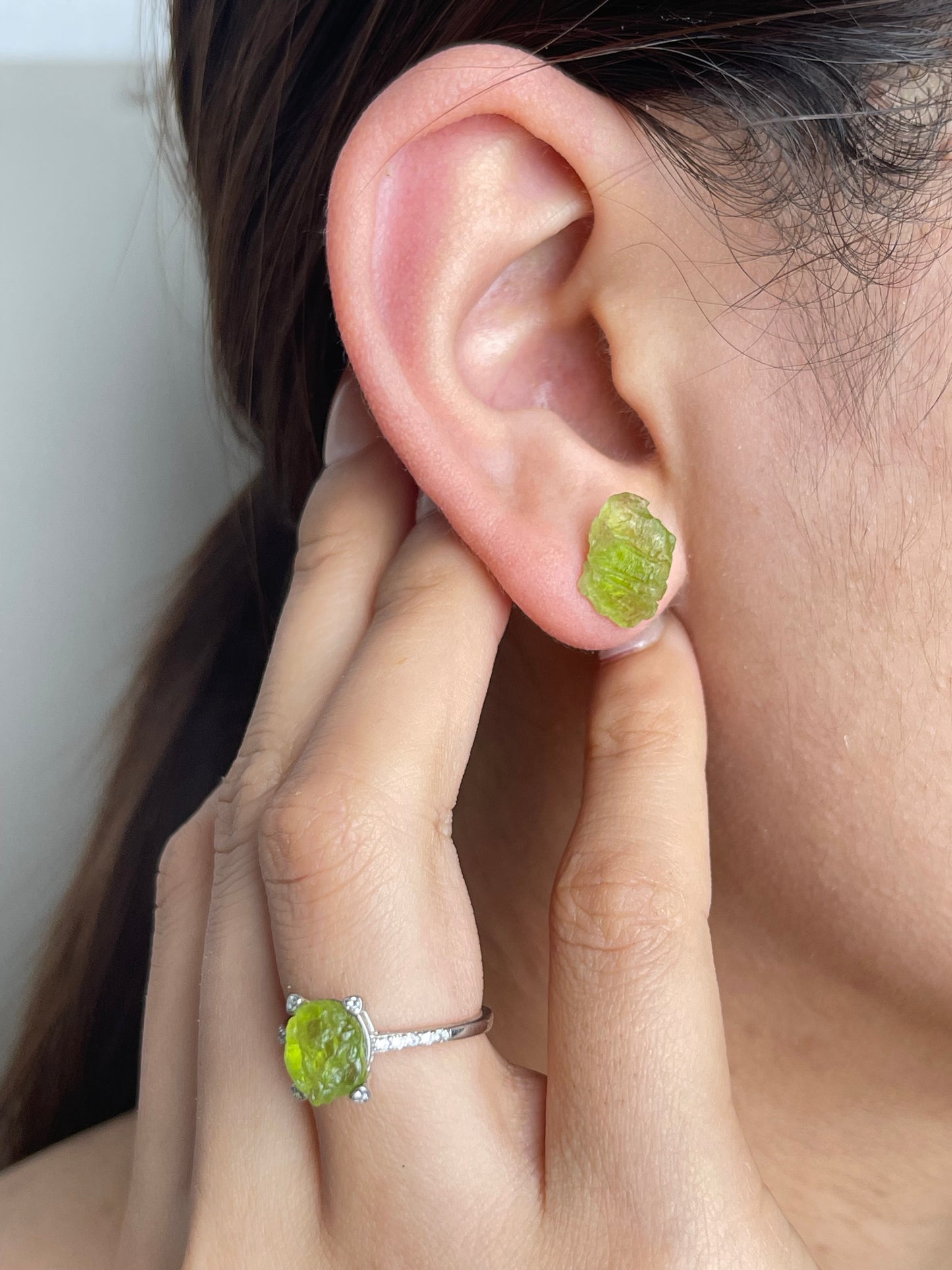 Raw Peridot Stud Earrings worn on ear