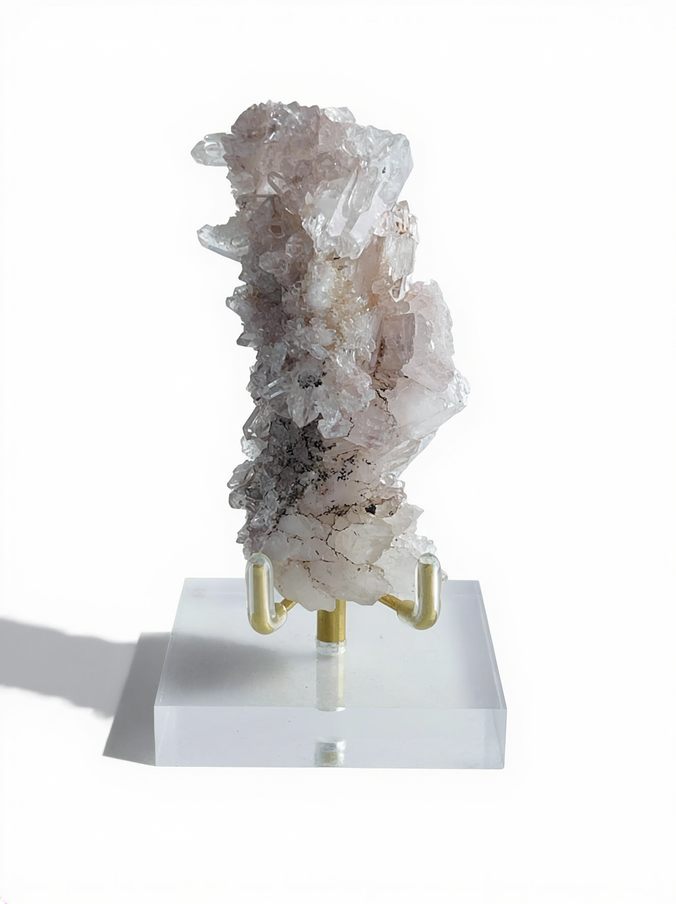 Raw Pink Lemurian Quartz cluster with manganese oxides on display stand, front view