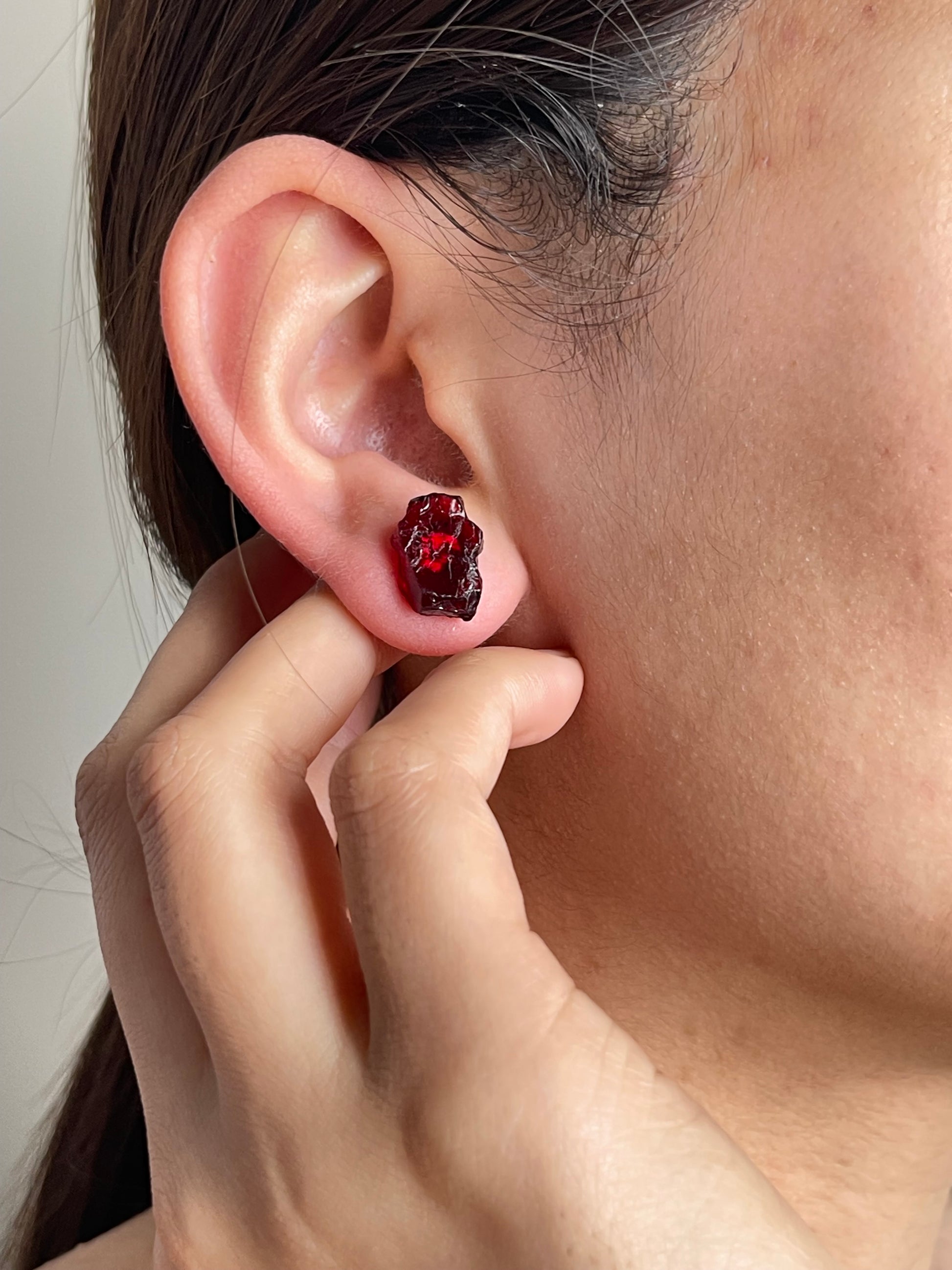 Close-up of raw Sri Lankan garnet stud earrings worn on ear