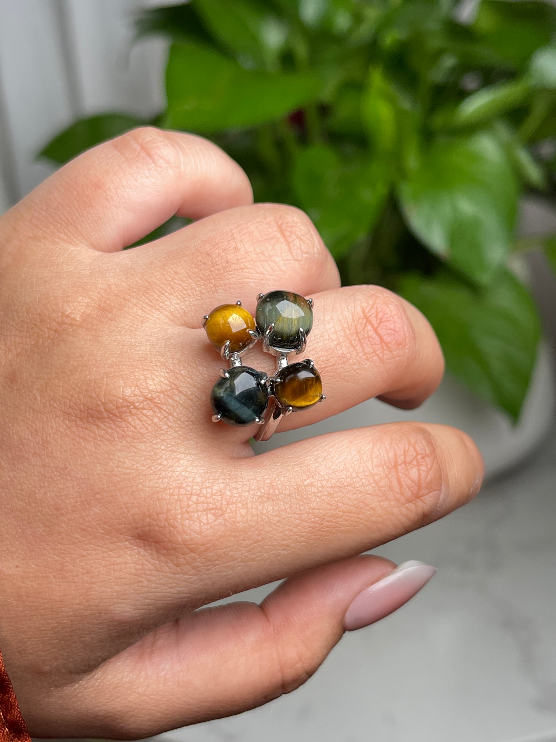 Close-up hand shot of tiger’s eye and blue tiger’s eye ring showing natural cat’s eye effect