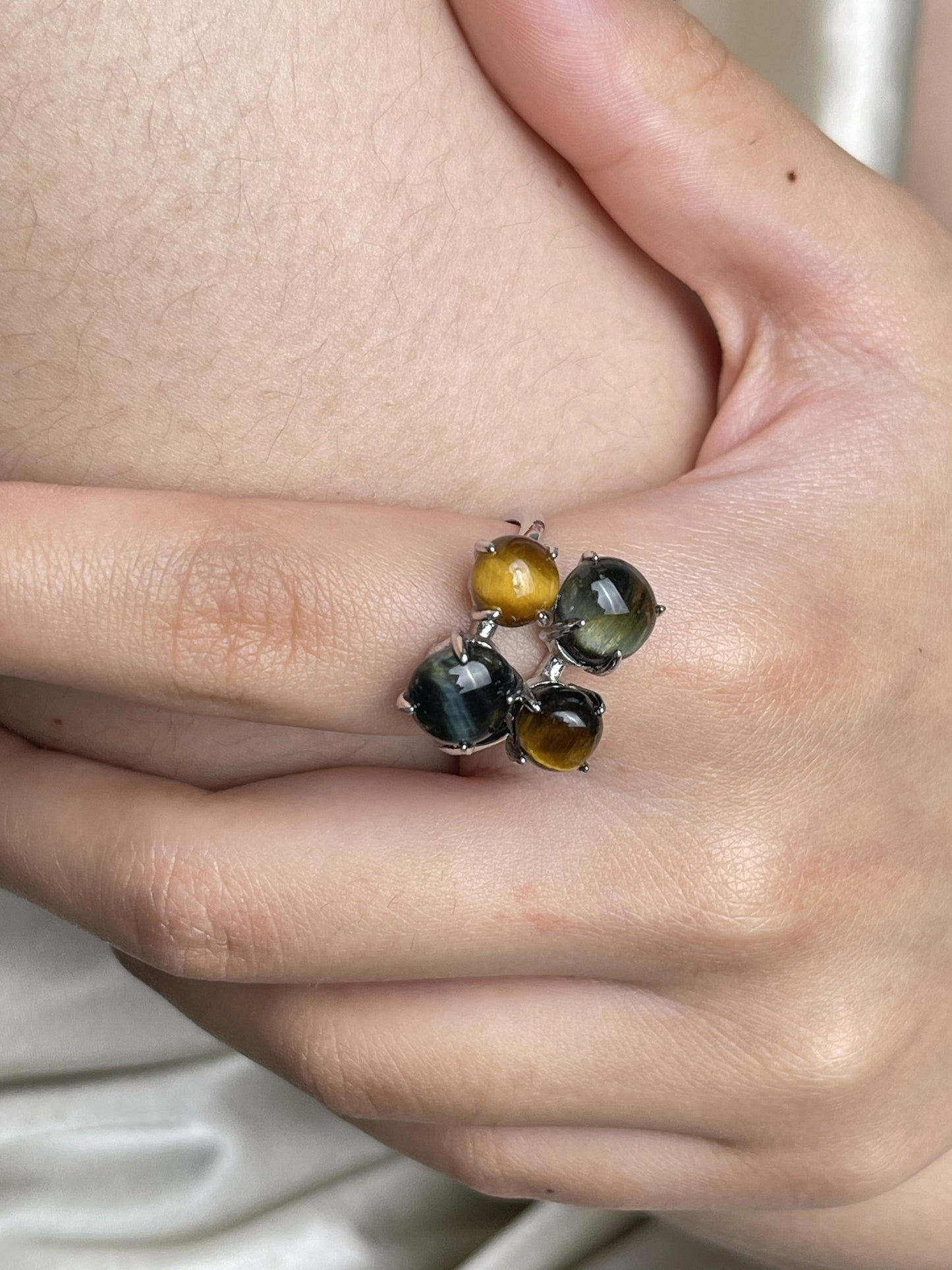 Close-up hand shot of tiger’s eye and blue tiger’s eye ring showing natural cat’s eye effect
