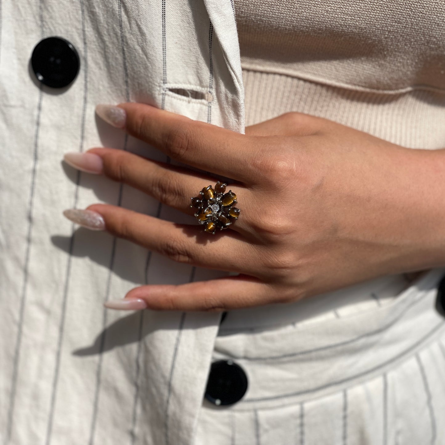 Close up of tiger’s eye cabochon cluster ring worn on hand