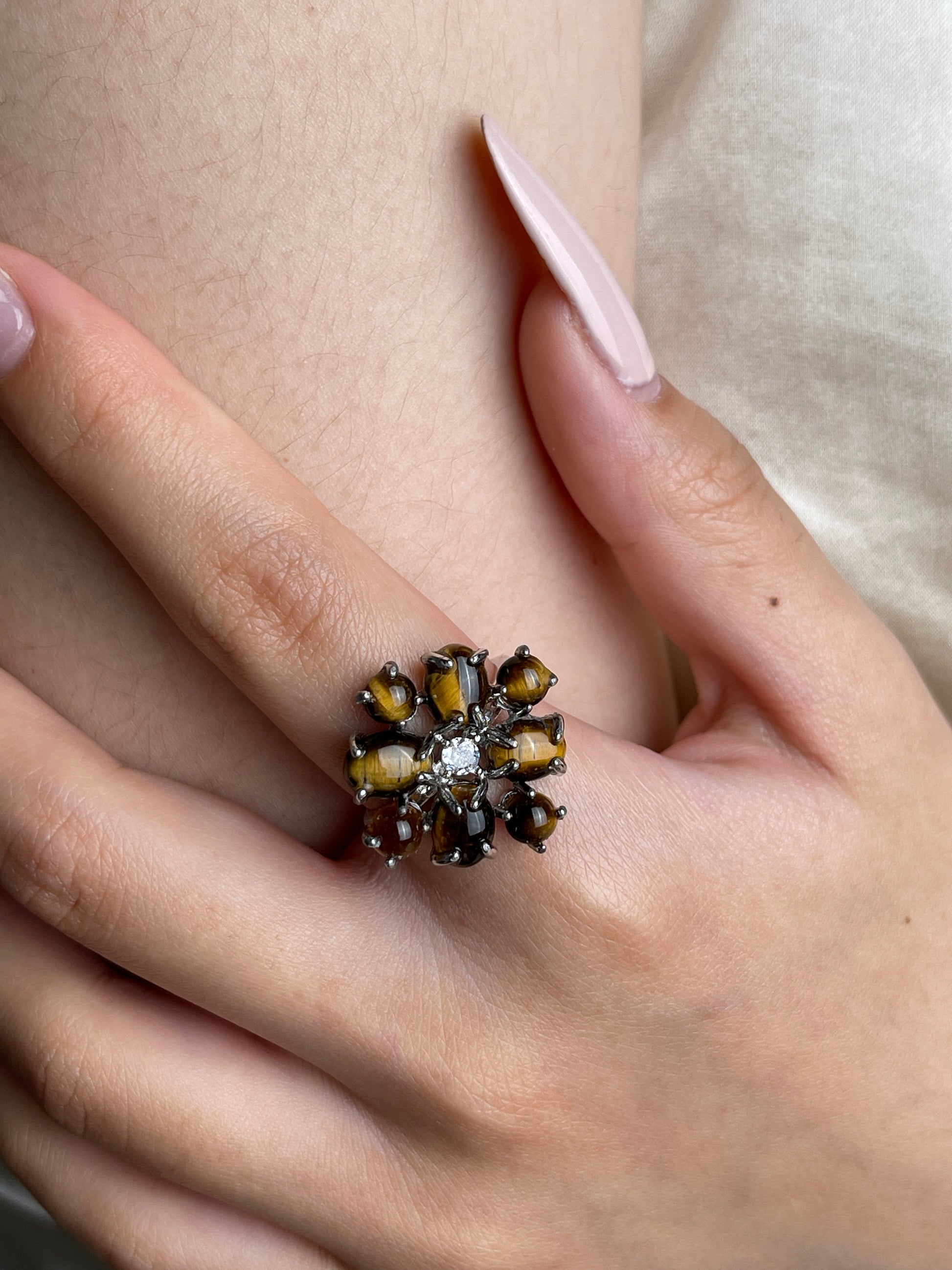 Close up of tiger’s eye cabochon cluster ring worn on hand